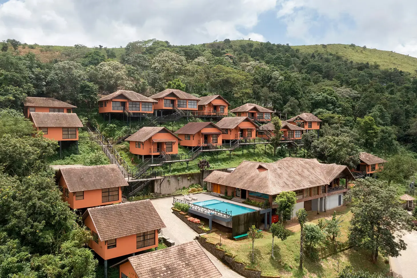 Aerial view of Thazhvaram Resort Homes across a green hillside in Panchalimedu